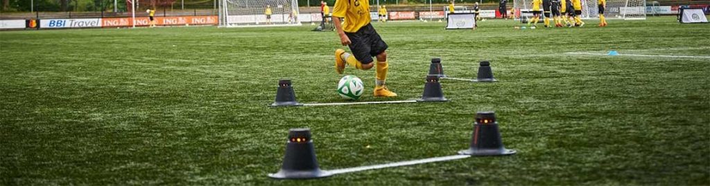 Athlete dribbling the ball through illuminated SMARTGOALS for cognitive training.